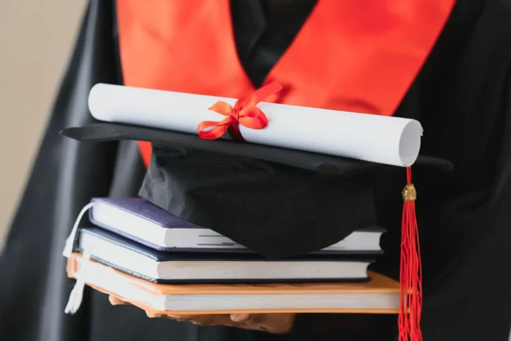 Une étudiante avec ses livres et carnets et son diplôme entre les mains, après la cérémonie de remise de diplôme