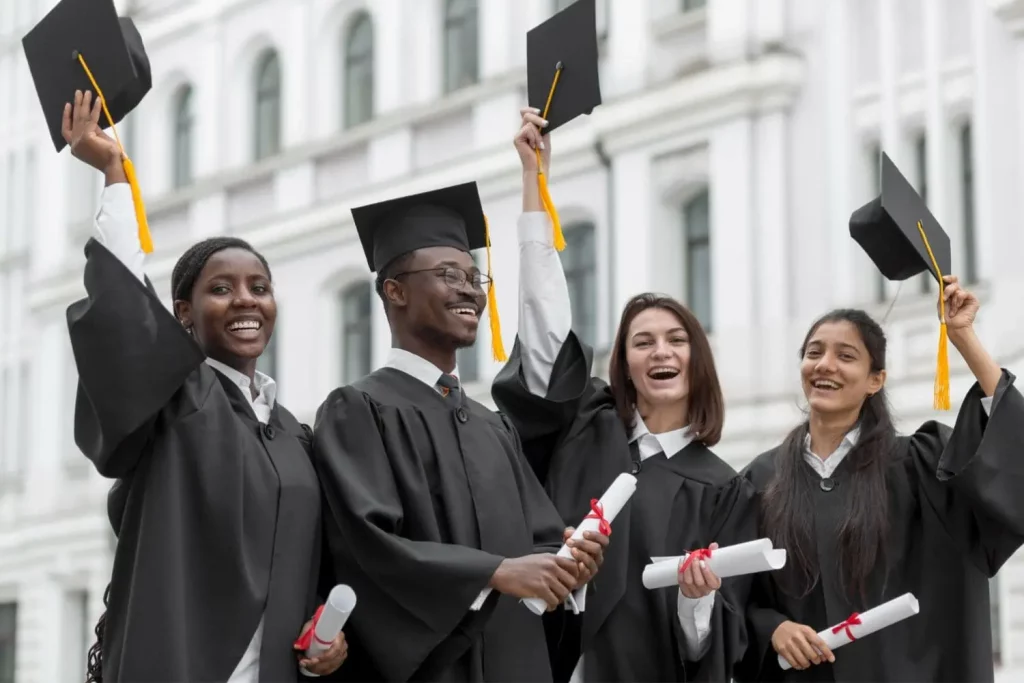 Un groupe de trois jeunes filles et d'un garçon diplômés heureux avec leurs diplômes