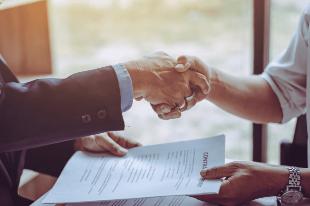 Deux personnes qui se tiennent la main après avoir signé un contrat de travail