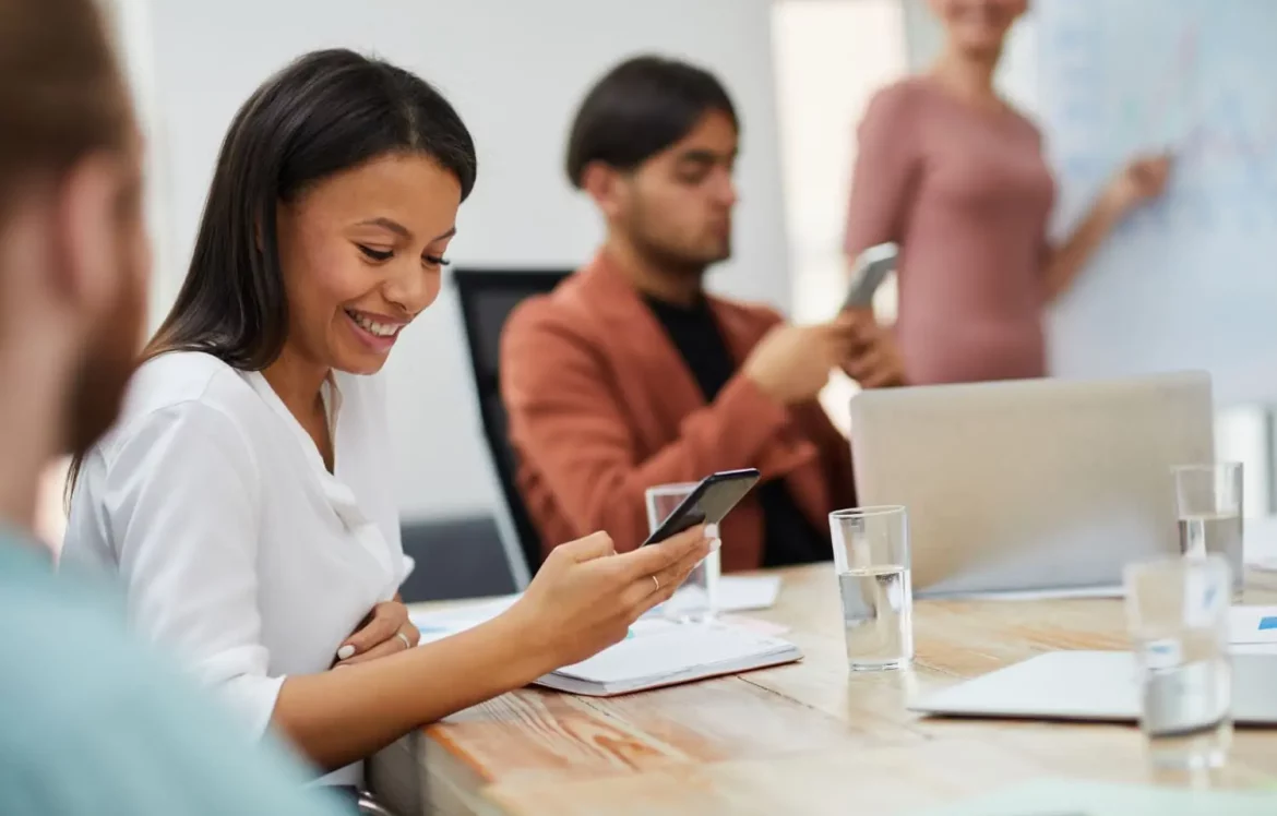 Une jeune fille qui sourit en regardant son téléphone pendant un cours au centre de formation