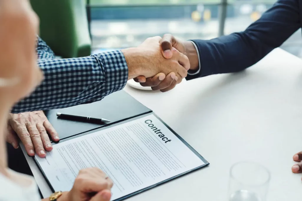 Deux personnes qui se serrent la main après la signature d'un contrat