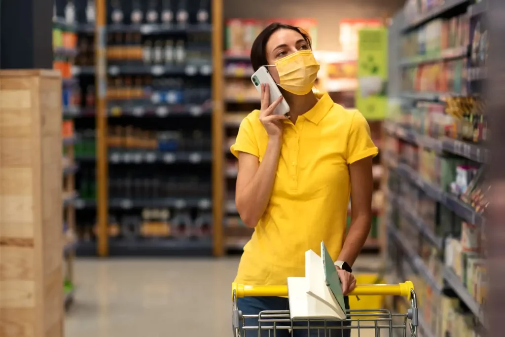 Une jeune fille qui travaille en rayon, avec un carnet de note et un téléphone