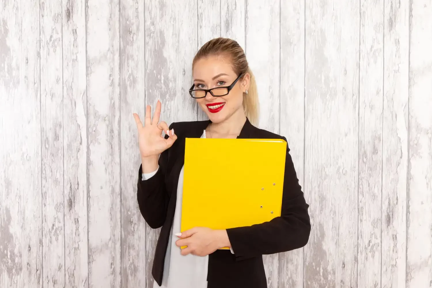 Une femme qui fait ok avec ses doigts et tient un classeur