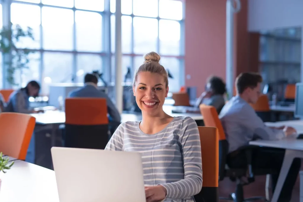 Une jeune femme souriante au travail derrière son ordinateur