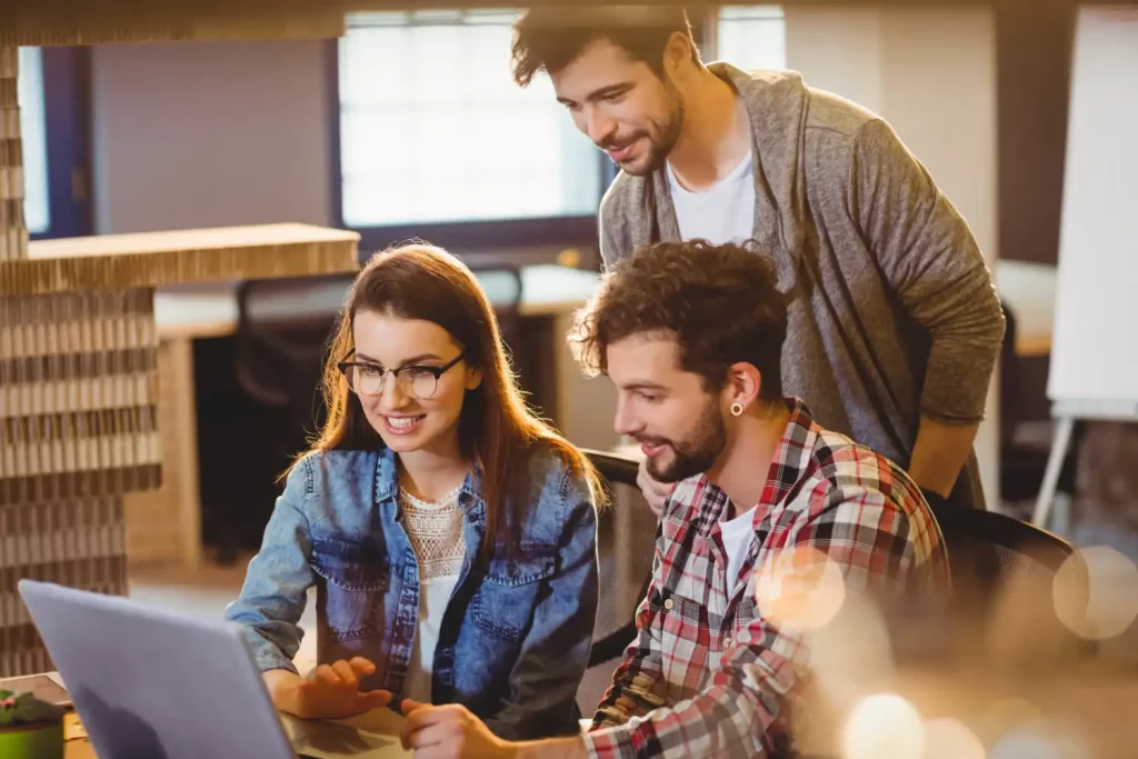 Jeune alternant qui travaille avec ses collaborateurs devant un ordinateur